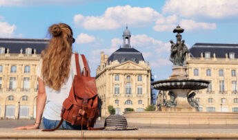 Woman student or tourist sitting on bench looking at Bourse square in Bordeaux France