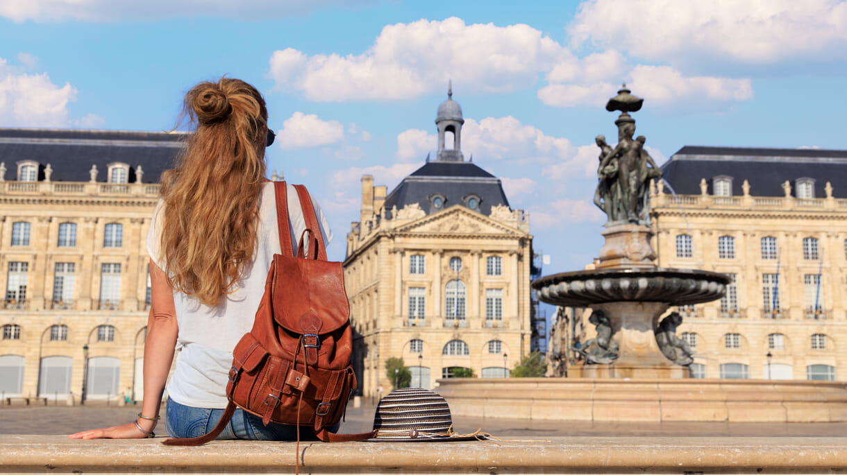 Woman student or tourist sitting on bench looking at Bourse square in Bordeaux France