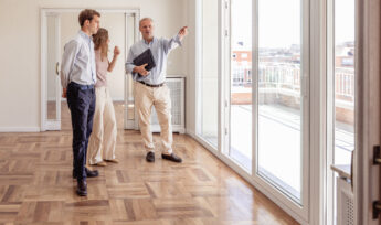 agent immobiliers faisant visiter un appartement éclairé à 2 potentiels locataires